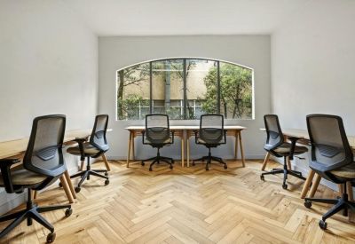 Bright open-plan office with multiple workstations and large arched window.
