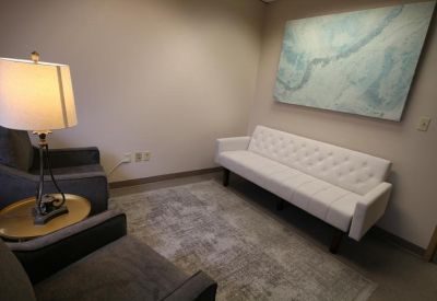Cozy lounge area with a white tufted sofa and blue abstract wall art.