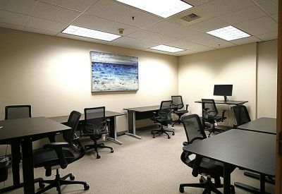 Spacious coworking area with multiple black mesh chairs and standing desks.