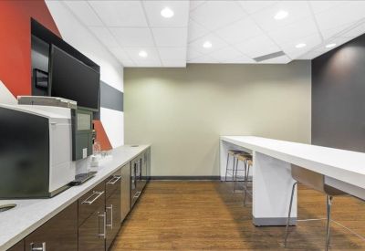 Modern breakroom featuring a white stone bar counter, wooden floors, and a red accent wall.