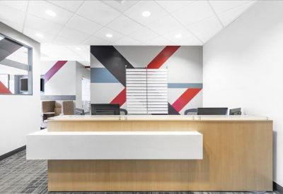Minimalist reception desk with a light wood finish and a geometric patterned wall.