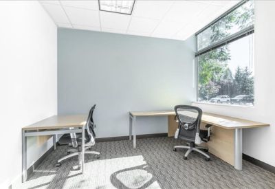 Two-person office suite with light wood desks and large windows for natural light.
