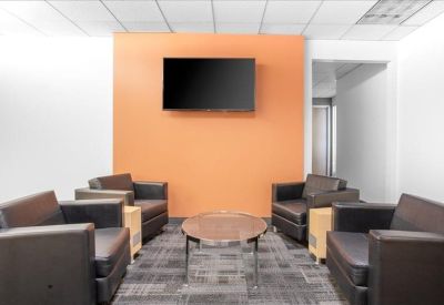 Lounge area featuring plush leather armchairs and a vibrant orange accent wall with a TV.
