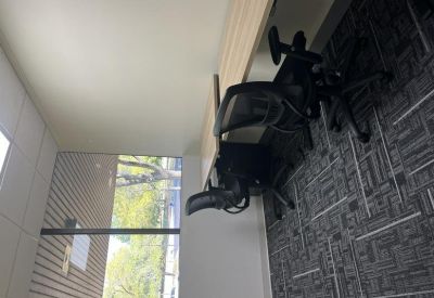Private office suite featuring a black mesh chair and a wooden desk near a large window.