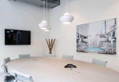 Minimalist meeting room with a large oval table and white pendant lights.