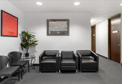 Waiting area with comfortable black leather armchairs and a framed art piece.