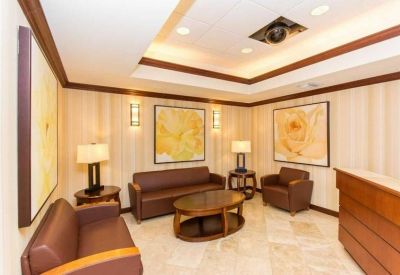 Reception lobby with brown leather seating, floral wall art, and warm lighting.