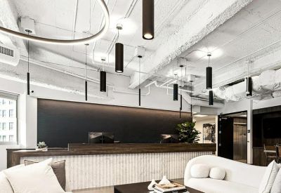 Spacious reception area with a wood-paneled desk, industrial ceilings, and modern pendant lighting.