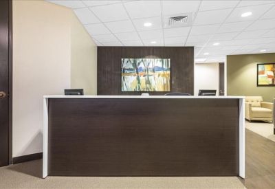 Modern reception area featuring a dark wood front desk and abstract framed artwork.