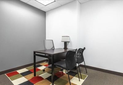 Private office suite with a dark wood desk and a colorful patterned rug.