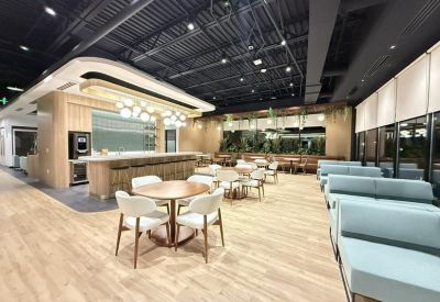 Spacious communal lounge and cafe area with wood floors, blue seating, and a modern bar at 23710, Schooler Plaza.