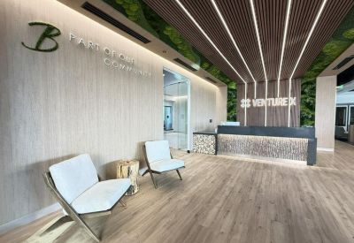 Modern reception area with a branded desk, sleek wooden walls, and contemporary white armchairs.