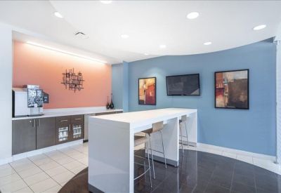 Modern breakroom featuring a white waterfall island, coffee station, and blue accent wall.