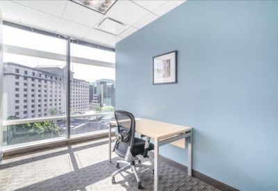 Private window office with a light blue accent wall and city views.