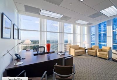 Spacious executive office with a large dark wood desk and seating area by floor-to-ceiling windows.