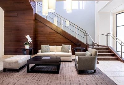 Spacious building lobby featuring a wooden staircase and comfortable lounge seating.