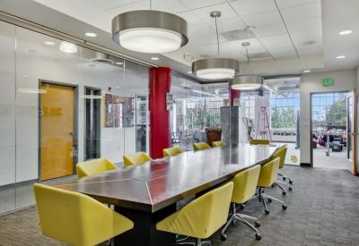 Meeting room with long wood table, yellow chairs, and glass walls.