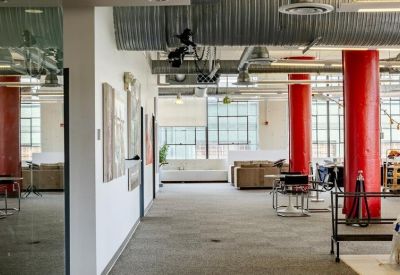 Open-plan office hallway with bright red columns and white sofas.