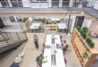 Spacious coworking area with communal tables, colorful chairs, and a mezzanine level.