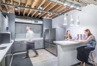 Reception lounge with blue armchairs, a patterned rug, and a modern service desk.