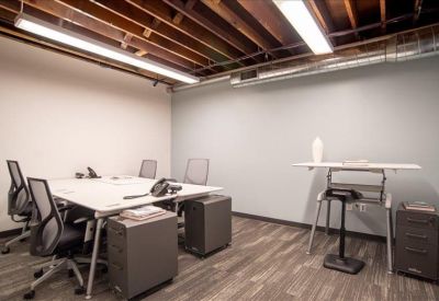 Private office with a white desk, grey chairs, and exposed wood beam ceiling.