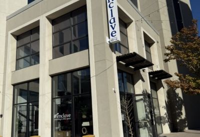 Exterior view of the modern glass and stone building at Enclave Coworking, 2421 West 7th Street.