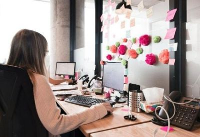Individual workstation featuring a dual monitor setup and a wall decorated with colorful sticky notes.