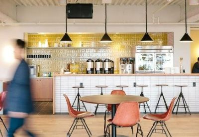 Modern café area with a white tiled bar, red chairs, and black pendant lights.