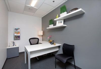 Private office featuring a white desk, grey accent wall, and floating shelves with plants.