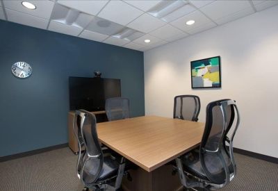 Small meeting room with a wooden table, ergonomic chairs, and a blue feature wall.