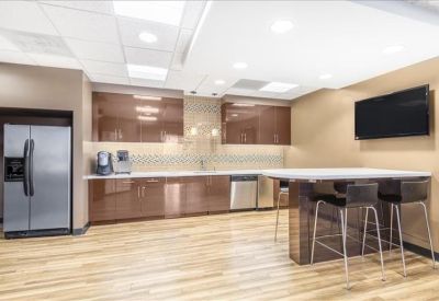 Modern kitchen and break area with wood floors, glossy cabinets, and a high-top island.