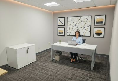 Bright private office with a grey desk, modern wall art, and a white storage cabinet.