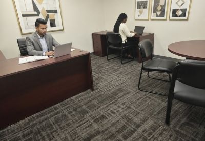 Shared office space featuring two dark wood desks and abstract framed artwork.