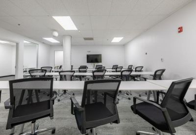 Training room with multiple white desks and ergonomic mesh chairs.