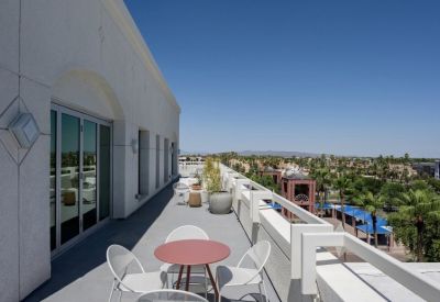 Spacious outdoor terrace with white seating, a red table, and views of the surrounding city.