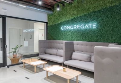 Waiting area with grey high-back sofas and a lush green plant wall.