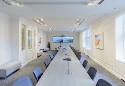 Long formal boardroom with light wood table and elegant wall molding.