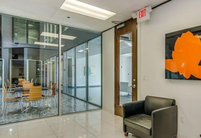 Modern waiting area featuring a black leather armchair and orange abstract wall art.