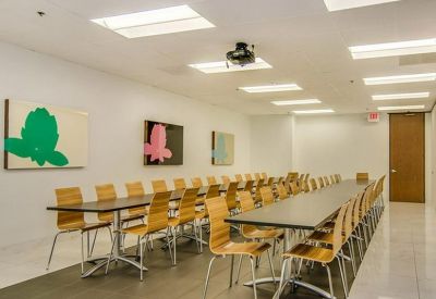 Large conference room with two long tables, wooden chairs, and colorful floral wall art.