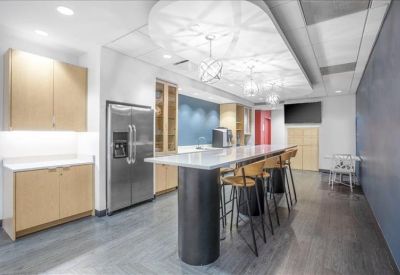 Modern communal kitchen and breakout area with a long island, bar stools, and stainless steel appliances.