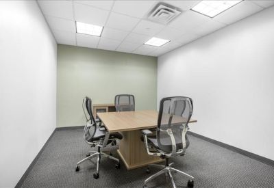 Meeting room with a central table, four mesh chairs, and recessed ceiling lighting.