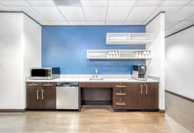 Modern breakroom kitchen with a blue accent wall and stainless steel appliances.