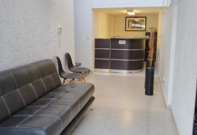 Modern reception area with a curved dark wood desk, leather sofa, and a skylight.