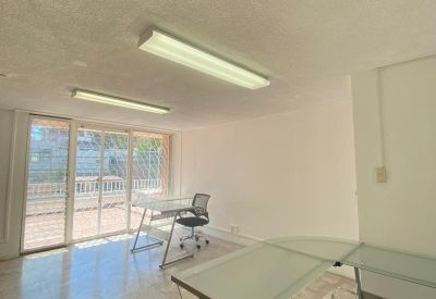 Bright workspace with glass desks, marble-style flooring, and large windows leading to a terrace.