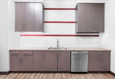 Modern kitchenette with wood-finish cabinetry and a stainless steel dishwasher.