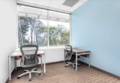 Bright private office suite with two desks and a light blue accent wall.