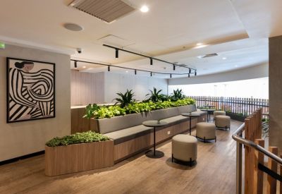 Relaxed lounge area with a built-in planter, grey bench seating, and modern art.