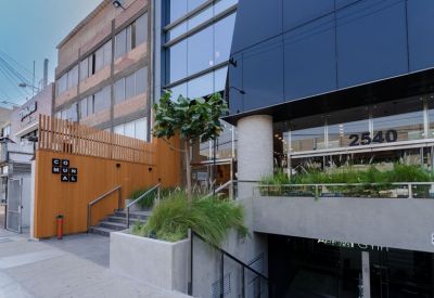 Main building entrance with wooden wall panels, greenery, and numbered signage.