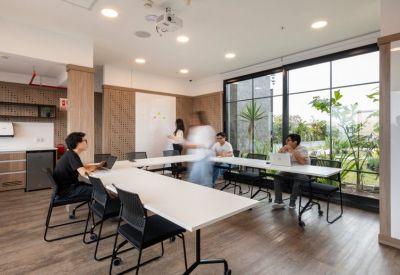 Collaborative office space with white tables, whiteboard, and large windows.