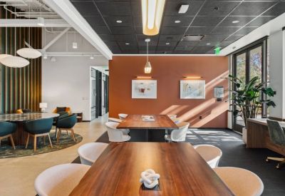 Coworking lounge with wooden tables, terracotta feature wall, and hanging designer lamps.